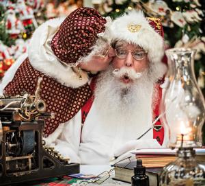 Santa getting a kiss on the cheek from Mrs. Claus