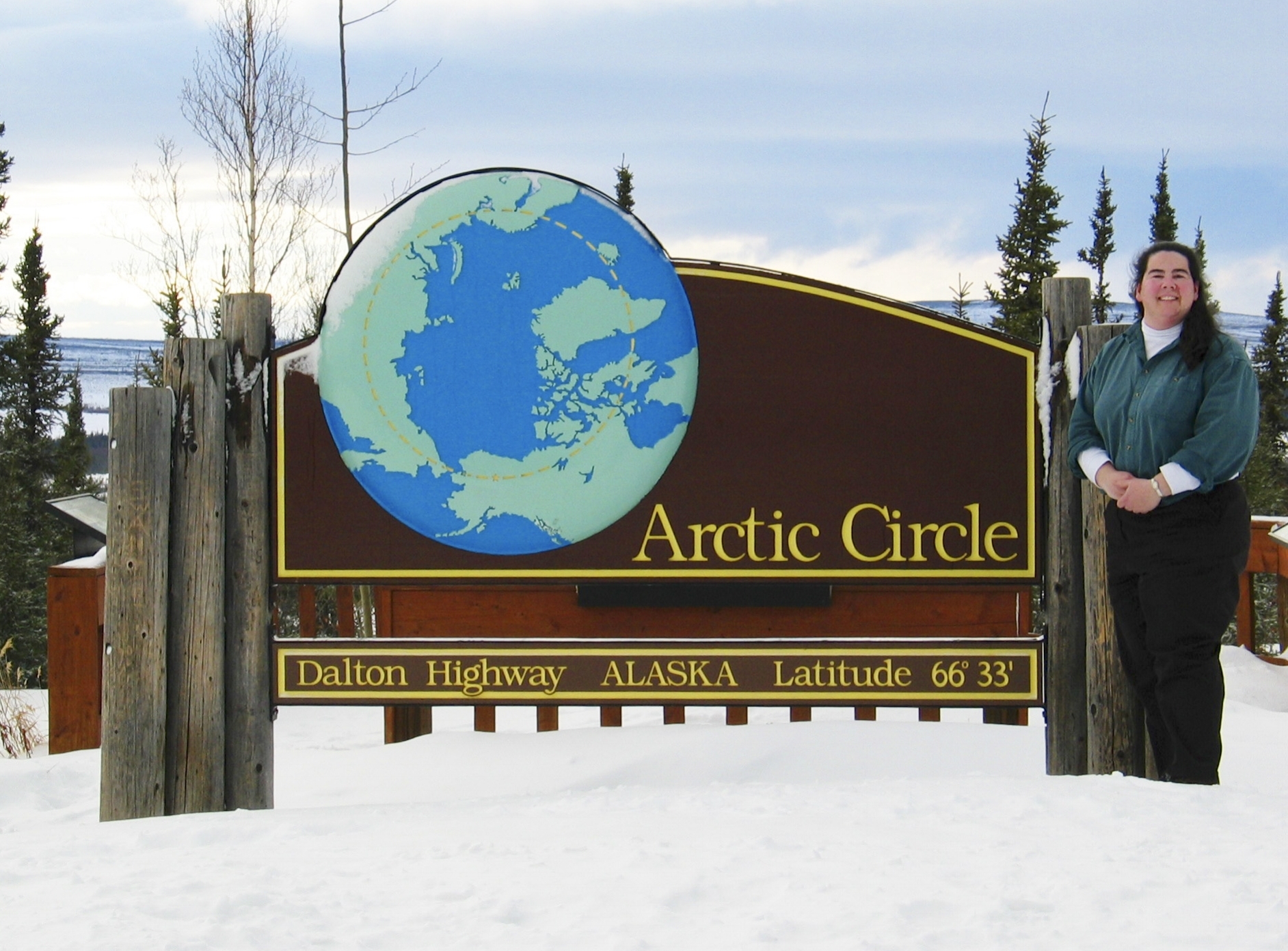 Person smiling next to Arctic Circle Sign in Winter