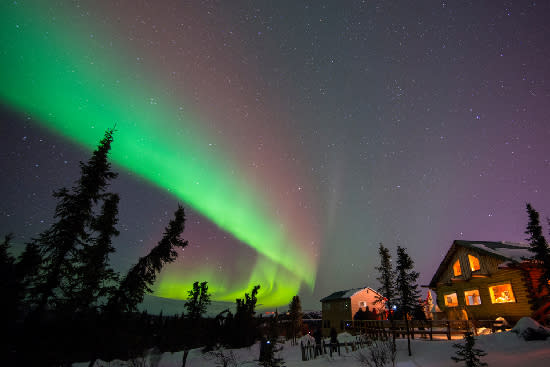 Green and pink aurora over cabin in Cleary Summit, Alaska