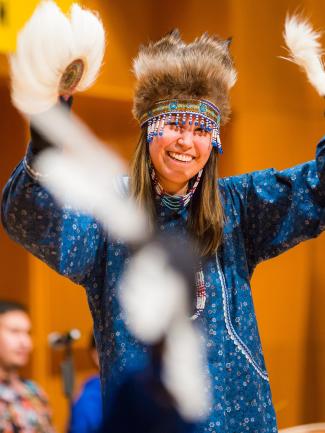 A dancer in traditional Alaska Native regalia smiles while performing with feathered fans during the Festival of Native Arts in Fairbanks.