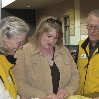 Two golden heart greeters looking at a guide with a visitor