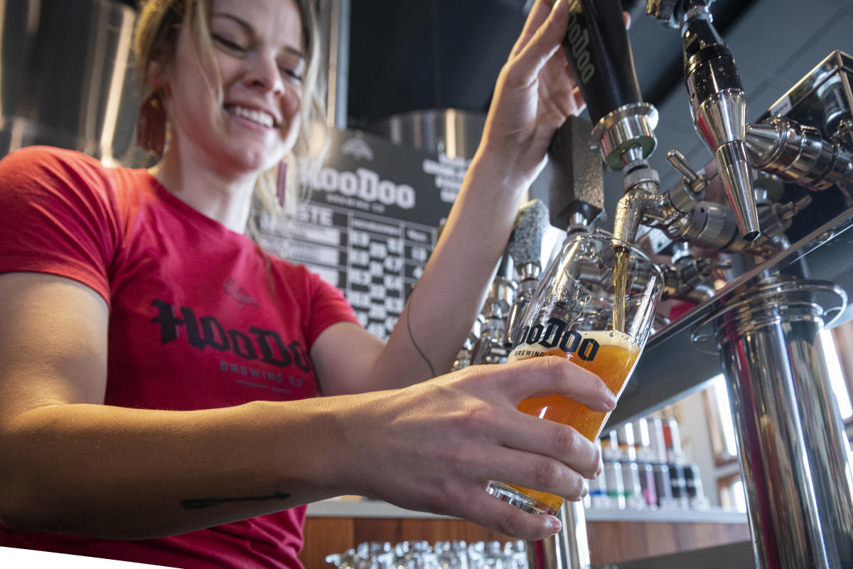 A bartender pouring a glass of beer at Hoodoo Brewing Company.