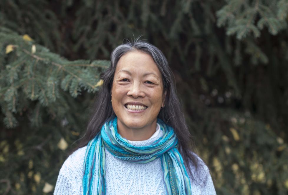 Portrait of person smiling in front of evergreen trees