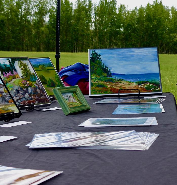 Amy Geiger/Explore Fairbanks Landscape paintings on an event table in a green park
