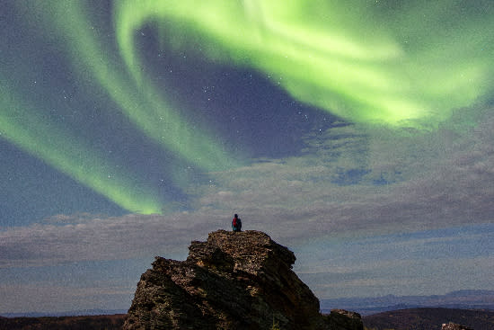 Person standing under vibrant fall aurora at Murphy Dome