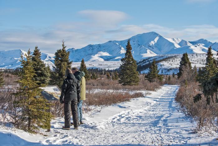 Two people walking on a snowy trail in Denali National Park