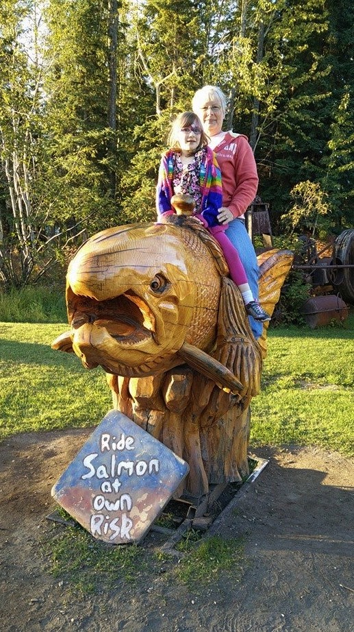 Child and grandparent on wooden salmon at Alaska Salmon Bake